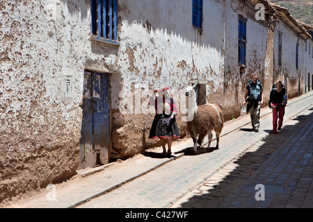 Peru, Cusco, Cuzco, Old Indian woman with llama and backpacker couple in San Blas district. UNESCO World Heritage Site. Stock Photo