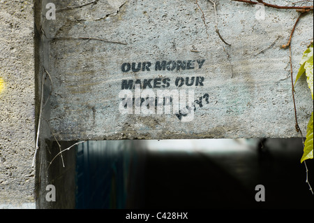 Stencil sprayed onto the stone of the Reichenbachbrücke in Munich showing the words 'Our money makes our world ...Why?', German Stock Photo