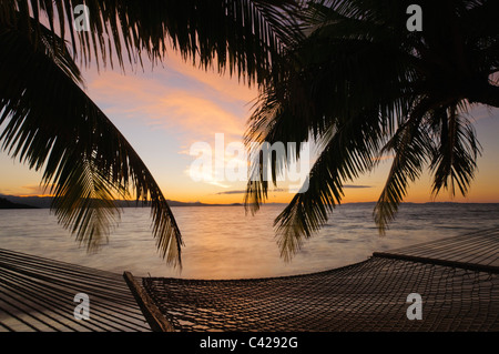 Hammock and palm trees on beach at sunset, Matangi Private Island Resort, Fiji. Stock Photo