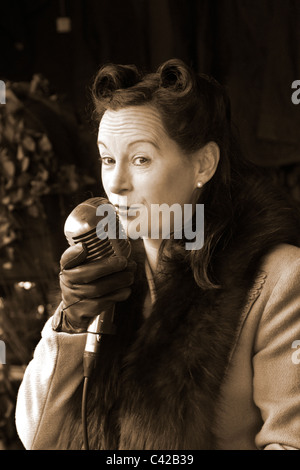 1940s WW2, WWII. World War two; Reenactor Katie Spitfire oortrait of a female singer holding an old type broadcast microphone, a wartime entertainer in a Re-enactment at a British Railway Station. The 40s Wartime Weekend actors, fashions & hairstyle at Rawtenstall Station, Lancashire, May 2011 Stock Photo