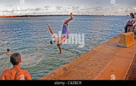 Young boys jumping and diving into the sea in Recife Brazil Stock Photo