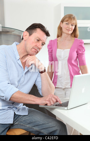 Man using laptop, woman looking at him. Stock Photo