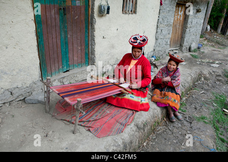 Peru, Patakancha, Patacancha, village near Ollantaytambo. Indian woman with daughter in traditional dress weaving. Stock Photo