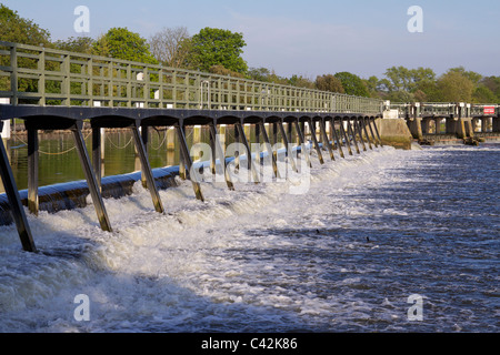 The weir at Teddington in the river Thames showing the tidal waters with trees in the background on a sunny afternoon Stock Photo