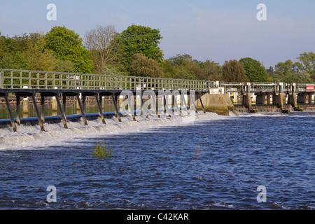 The weir at Teddington in the river Thames showing the tidal waters with trees in the background on a sunny afternoon Stock Photo