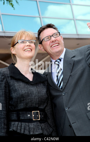 Mature business woman and man wearing glasses, outside smiling. Stock Photo