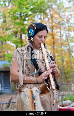 Woman dressed as Native American Indian plays hand made wooden flute at Billie Creek Village in Rockville, Indiana, USA Stock Photo