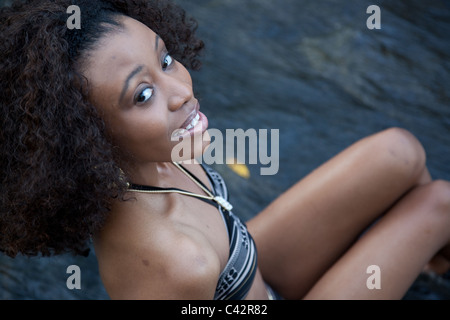 Pretty black woman wearing a swim suit and sitting in a stream as