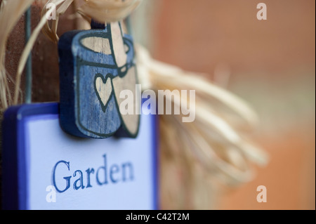 Garden more work less sign hanging on a brick wall Stock Photo