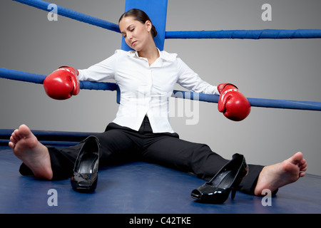 Portrait of tired businesswoman in boxing gloves sleeping on boxing ring Stock Photo