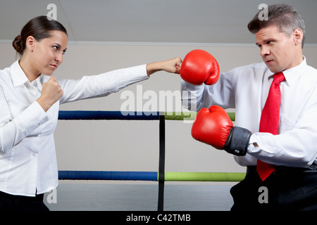 Portrait of aggressive businessman in boxing gloves fighting with serious female Stock Photo