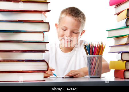 Portrait of cute youngster sitting among stacks of literature and drawing Stock Photo