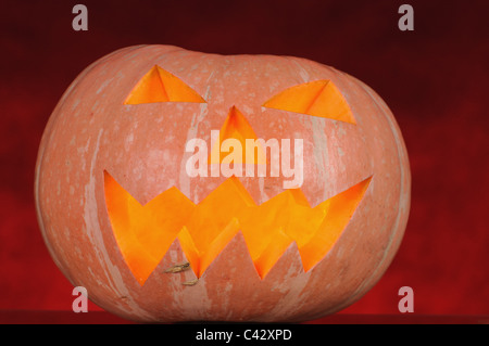 pumpkin with lighting candle inside on red background Stock Photo