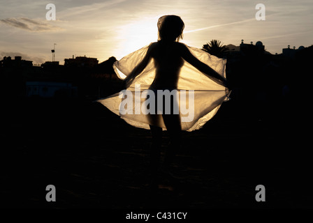 dancing woman silhouetted against the setting sun Stock Photo