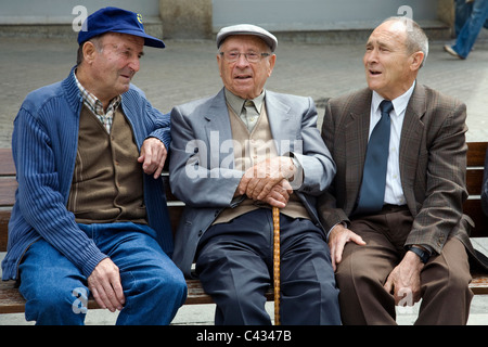 Three Catalan men sat talking on a bench Stock Photo