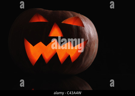 pumpkin with lighting candle inside on black background Stock Photo