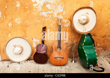Mexican musical instruments and sombreros rest against a shabby wall with peeling paint Stock Photo
