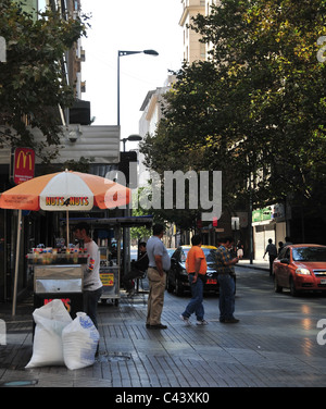 Urban street view people umbrella stand vendor cooking fast-food roasted nuts ice-cream pop-corn, Paseo Ahumada, Santiago, Chile Stock Photo