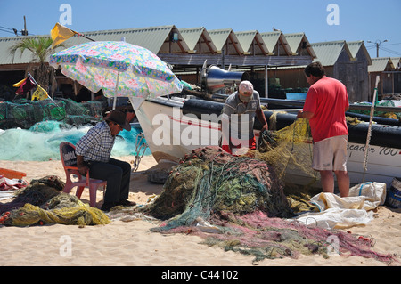 Fishermen mending nets on beach, Armação de Pêra, Algarve Region, Portugal Stock Photo