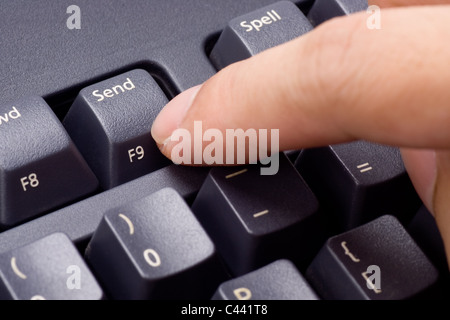 Closeup of a finger pressing SEND button on a keyboard Stock Photo