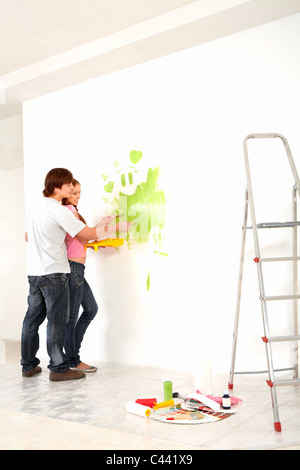 Affectionate couple helping each other to paint walls in new house Stock Photo