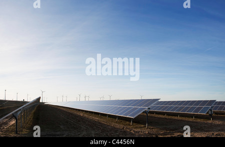 Solar panels in a field and wind turbines in the distance Stock Photo