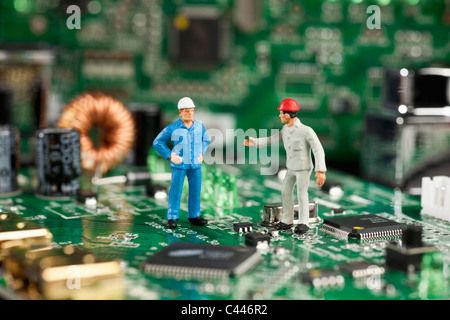 Two miniature figurine men working on a computer mother board Stock Photo