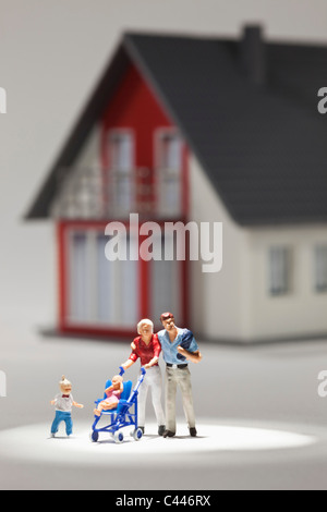 A young family of miniature figurines in front of a house Stock Photo