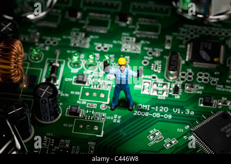 A miniature figurine construction worker standing on a computer mother board Stock Photo