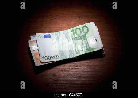 Stack of money on a spot lit table Stock Photo