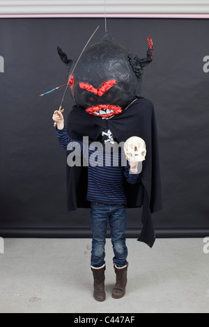 Kid with Halloween outfit on, a skull in his hand and a toy sword Stock Photo