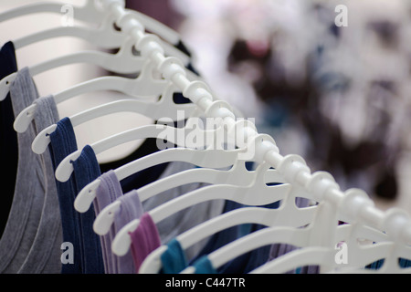 A row of t-shirts hanging on hangers in a retail shop Stock Photo