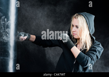Blond boxing woman in black training with punching bag Stock Photo