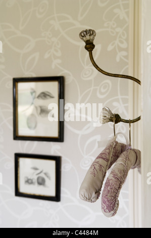 Padded coat hangers on hook on the back of a door in bedroom with patterned wallpaper Stock Photo