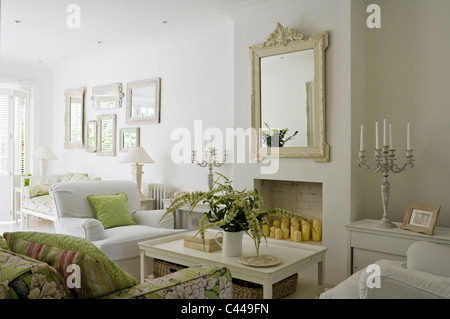 White living room with coffee table, mirror and floral patterned sofa. Stock Photo