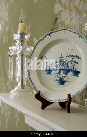 Blue and white chinese dining plate displayed on mantelpiece with glass candlestick Stock Photo
