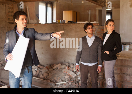 An architect showing a couple around a building site Stock Photo