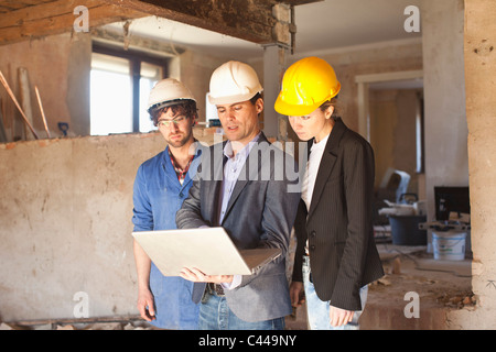 A building contractor and architects looking at a laptop at a building site Stock Photo