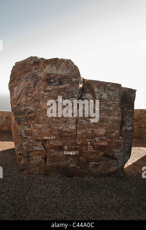 Boulder with written messages on it and surrounding wall in the background Stock Photo