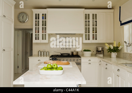 Marble topped island in kitchen with white units and tiles Stock Photo