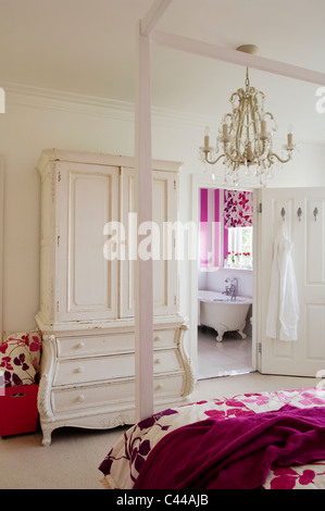 Fourposter bed in bedroom with white wardrobe with drawers, chandelier and en suite Stock Photo