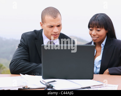A businessman and a businesswoman using a laptop together Stock Photo