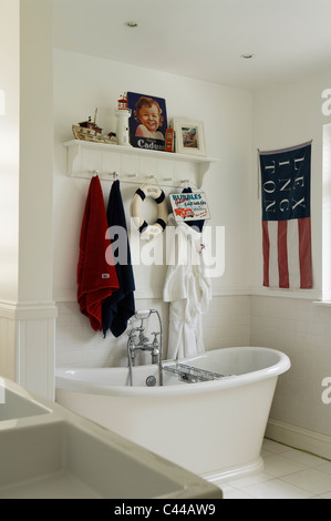 Freestanding roll top bath tub in white bathroom with American style flag and towel rack Stock Photo