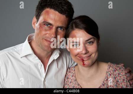 A bruised and beaten couple smiling cheerfully at the camera Stock Photo