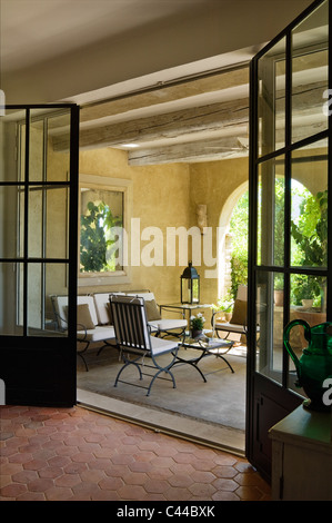View through glass paned double doors out onto loggia with beamed ceiling, lanterns and outdoor furniture Stock Photo