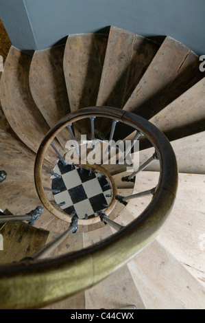 View down spiral oak staircase with banister and checked floor at the bottom Stock Photo