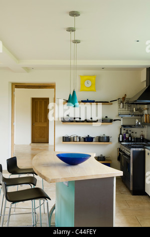Barstools at wooden topped island in modern kitchen with turquoise pendant lights Stock Photo