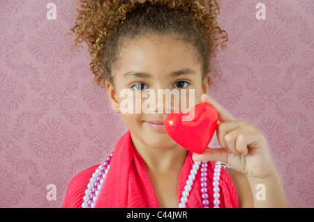 young girl holding a heart in a pink room