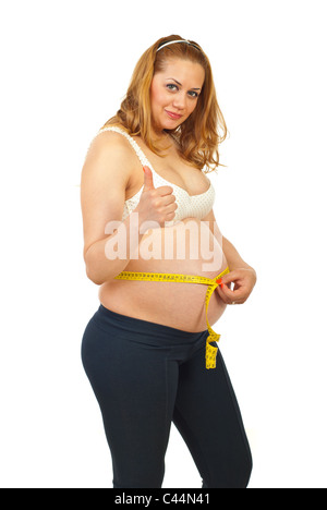 Happy pregnant woman in seven months measure her tummy with centimeter and giving thumbs up isolated on white background Stock Photo