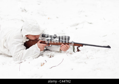 Sniper in white camouflage aiming on snow. Stock Photo